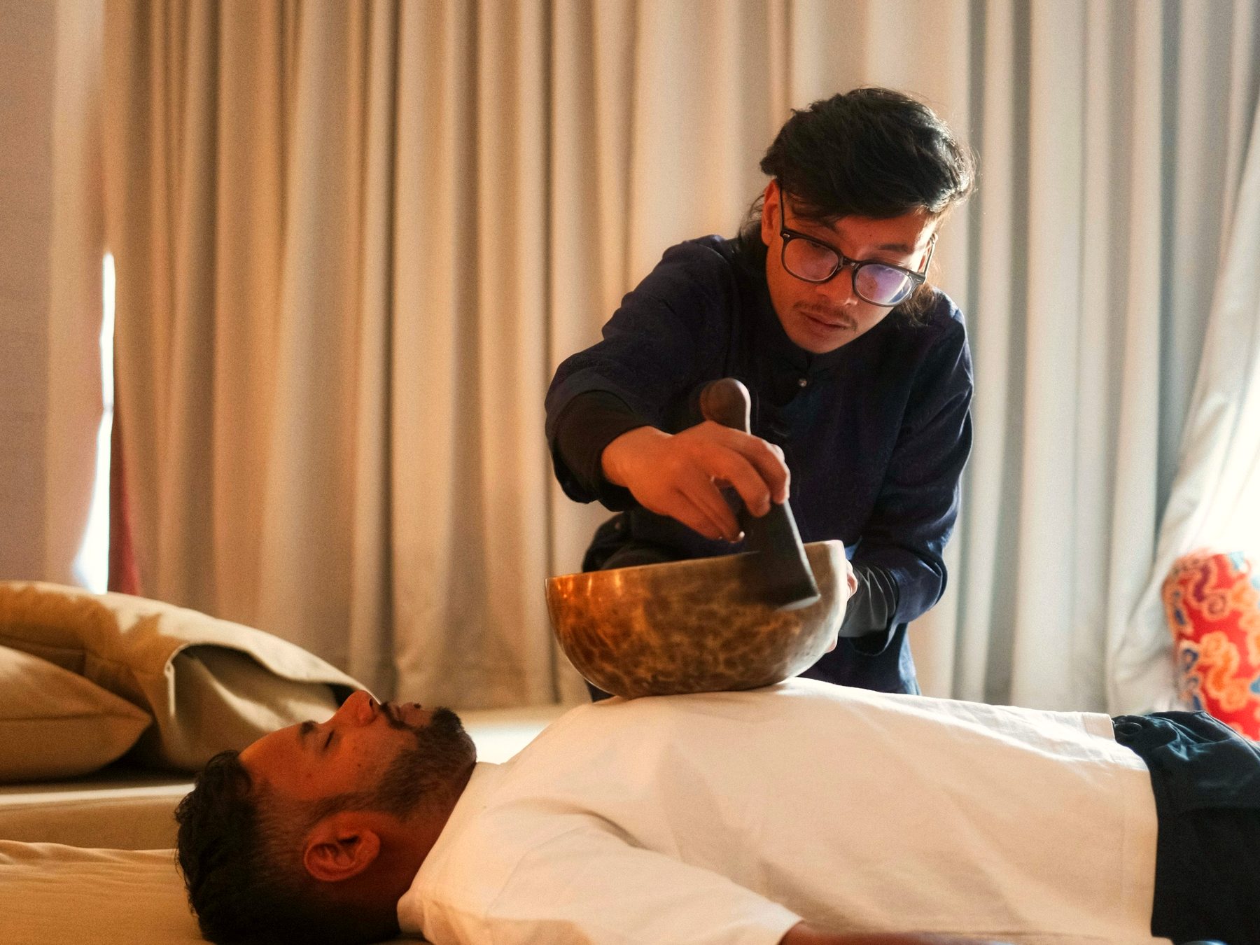 A sound healer resting a singing bowl on a client's chest