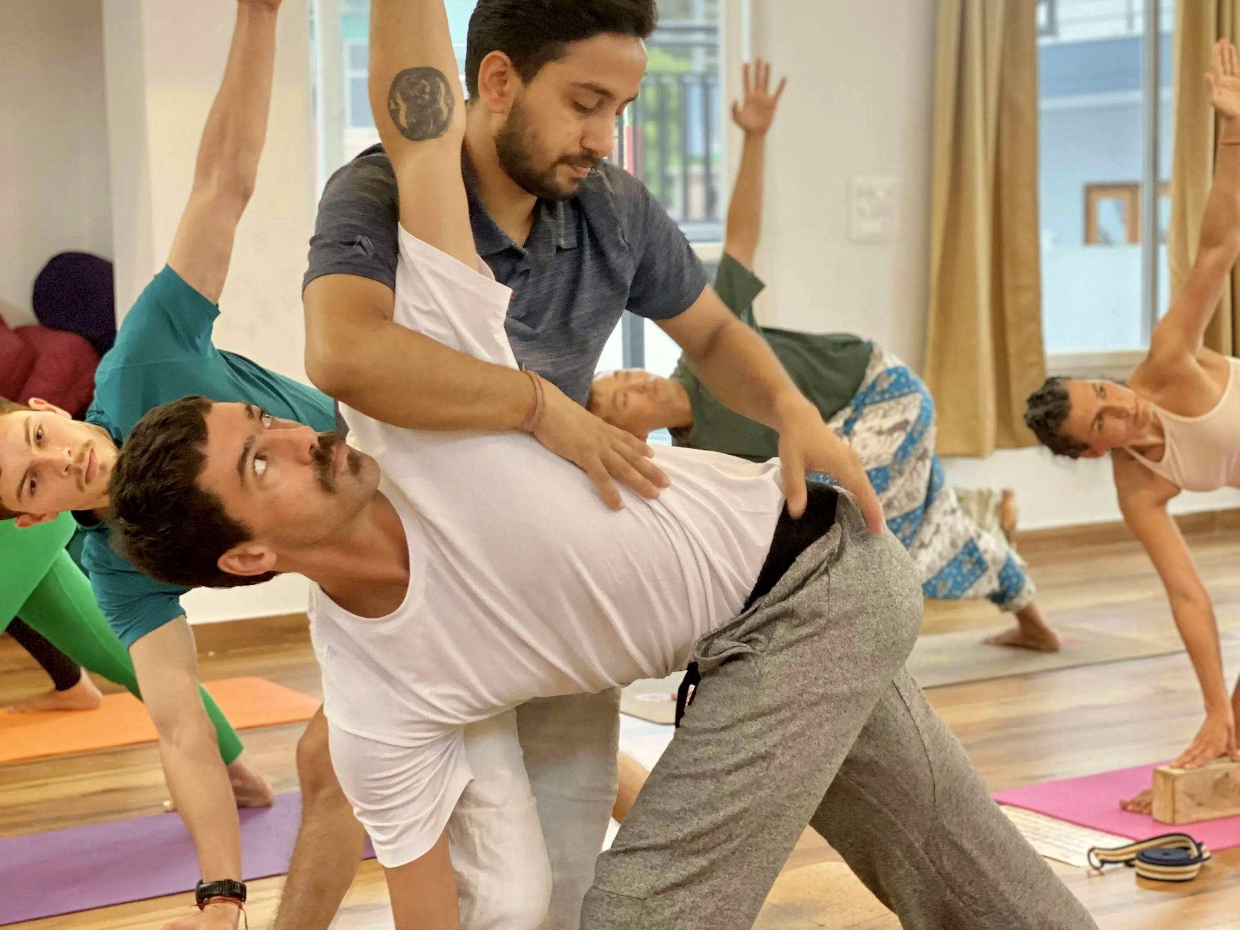 A yoga instructor adjusting a student in class